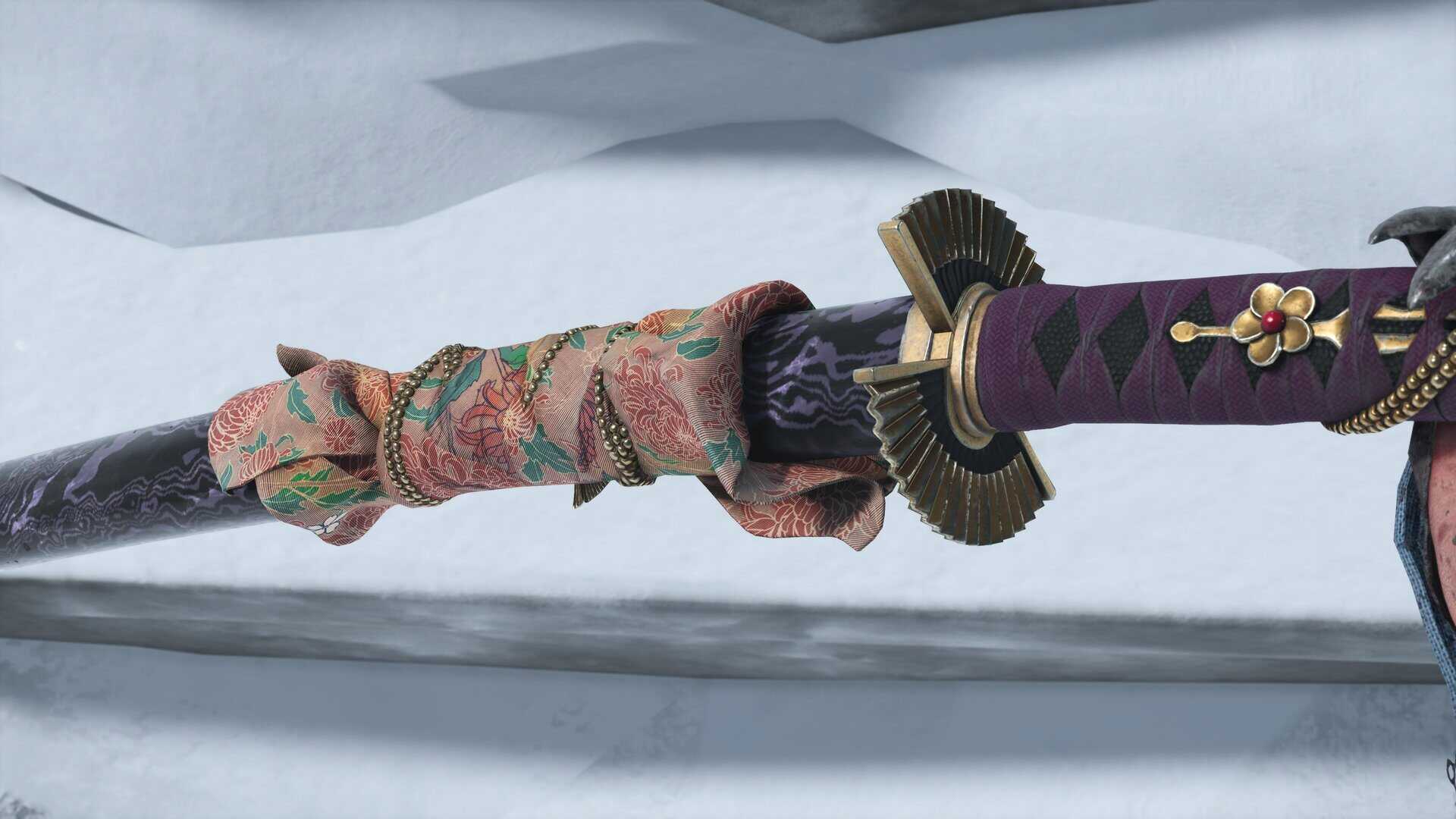 A close up of an ornate scabbard for a katana, wrapped with a length of patterned silk, along with an ornate tsuba and hilt for the katana itself.