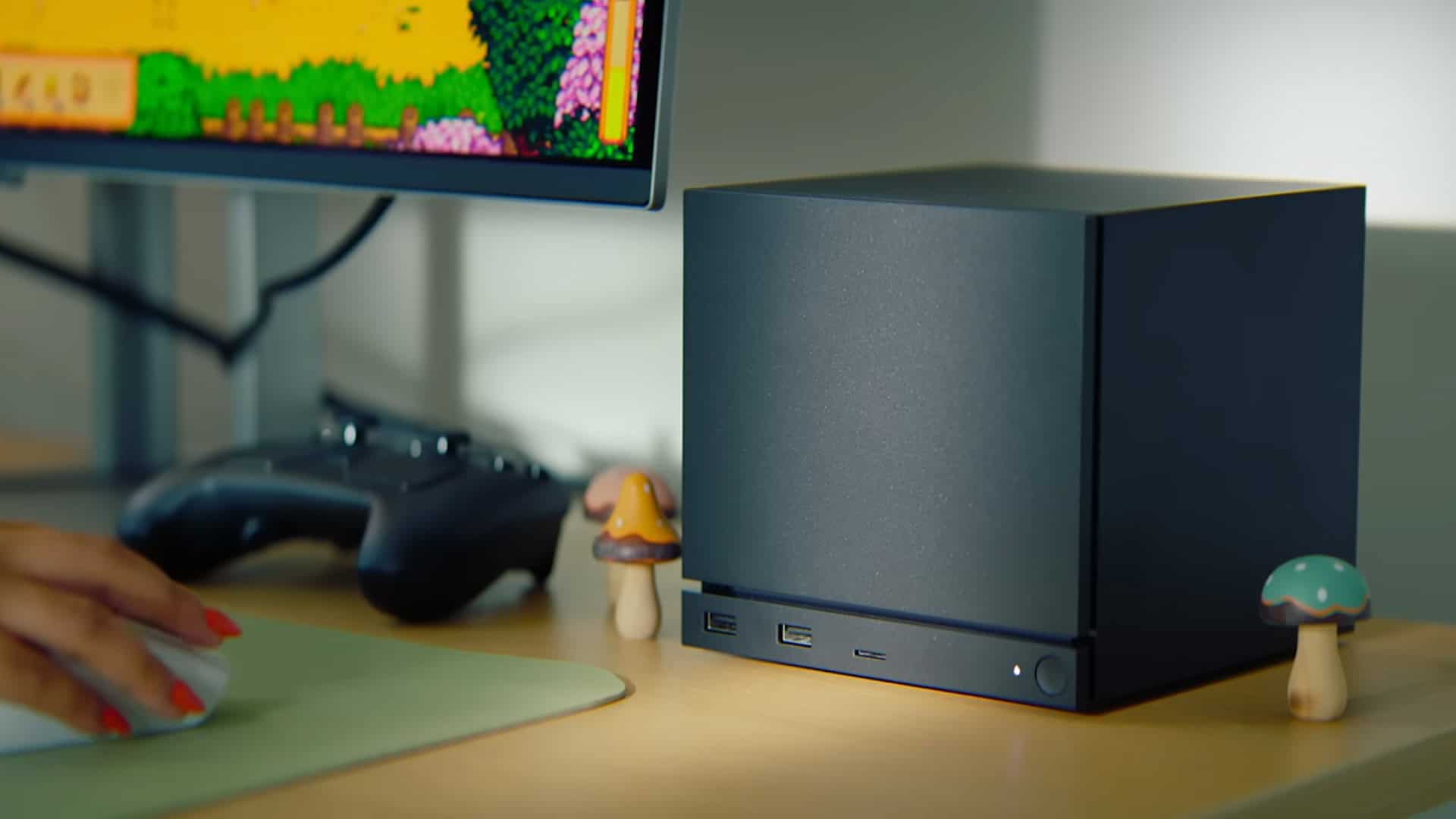 A Steam Machine on desk next to a PC and some mushroom decorations